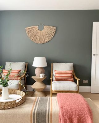A pink a grey living room with a grey accent wall and soft neutral lounge chairs
