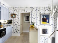 Blue kitchen ideas illustrated by a blue and white chevron wallpaper, pale blue cabinetry and white and yellow accents.