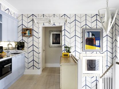 Blue kitchen ideas illustrated by a blue and white chevron wallpaper, pale blue cabinetry and white and yellow accents.