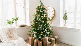 a gold and white christmas tree in the corner of a living room, with presents underneath