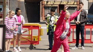 Bernie Winter running through the street with her arms up as onlookers smile at her.