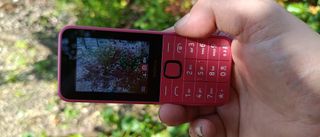 Hand holding Nokia 225 4G (2024) phone in garden