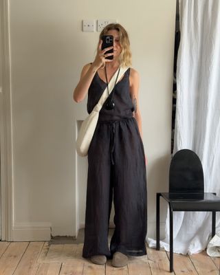 Woman wears a black Leset tank top and pants and The Row Hugo suede mules.