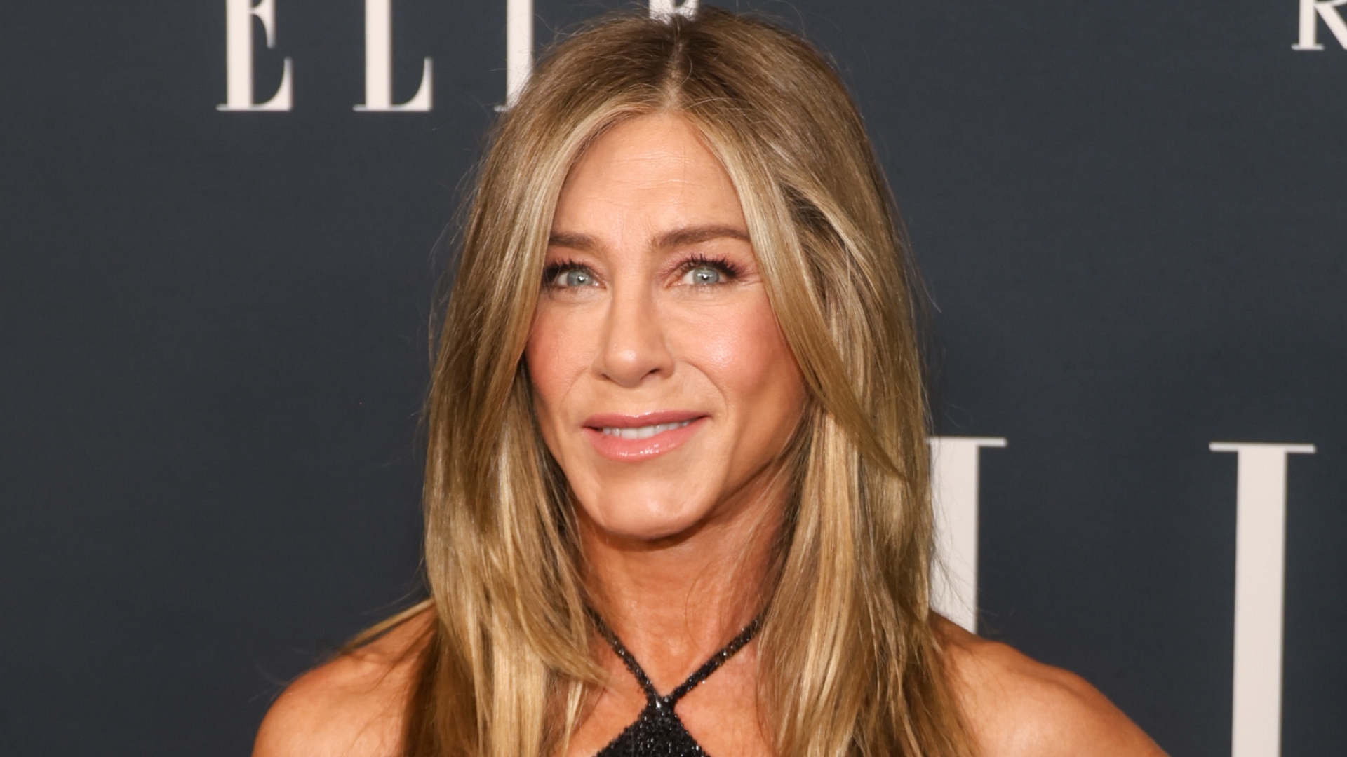 Image of Jennifer Aniston smiling with straight layered blonde hair and wearing a black halterneck dress