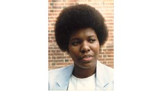 Barbara A. Williams looks off to her right while standing in front of a brick wall.