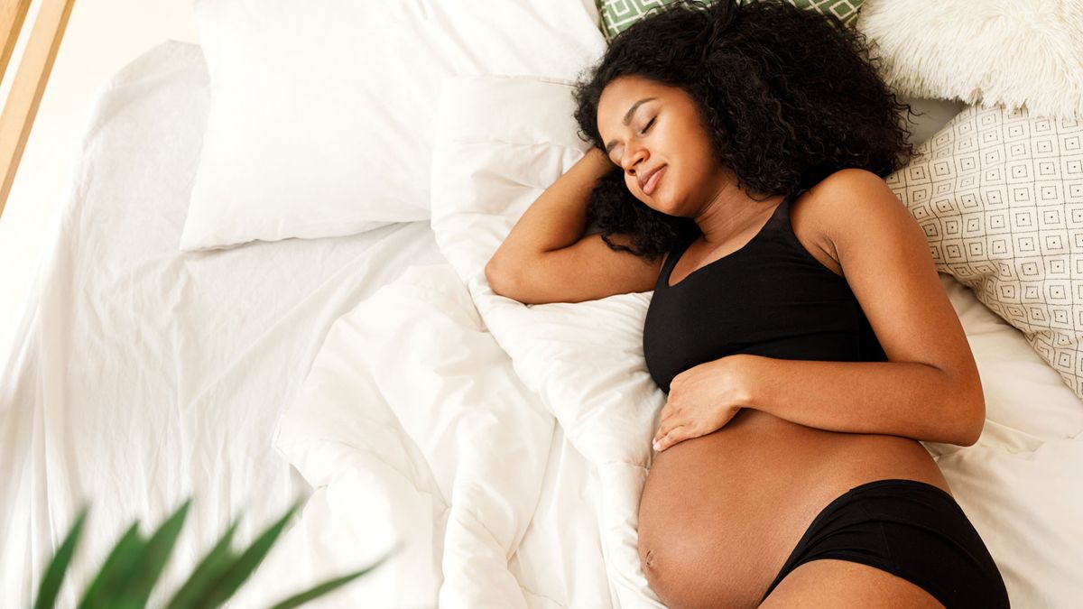 How should you sleep during pregnancy? Image shows pregnant woman sleeping on her side