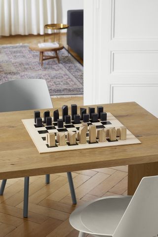 Nona chess set by E15 with oak pieces and a leather board, on table in living space