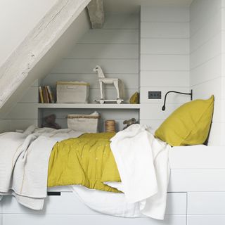 bedroom with white striped wall white bed with yellow and white cushions