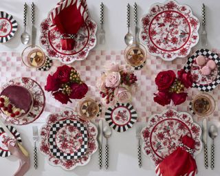 A black, red, and pink tablescape with lots of different patterns and three rose centerpieces