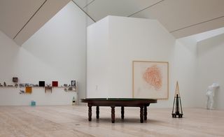 White room with wooden table and art sculptures/paintings