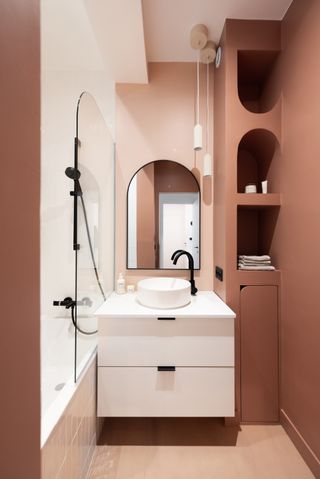 terracotta pink bathroom with white vanity and bath paired with black fixtures