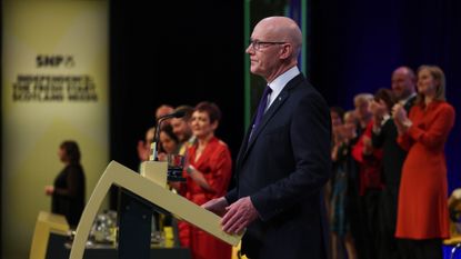 John Swinney speaking at a podium during the SNP party conference in 2025
