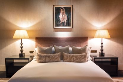 Bed with white and red geometric decorative cushions and an image of a girl in a headscarf above the headboard