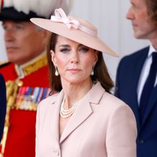 Prince William wears a suit and Kate Middleton wears a pale pink suit and matching hat