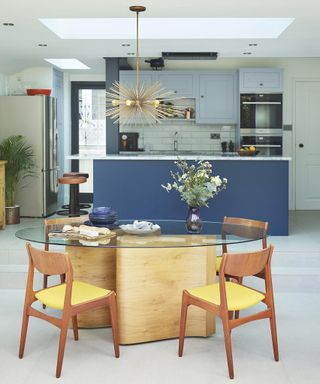 Ambient lighting in a blue kitchen with glass table showing how to plan kitchen lighting.