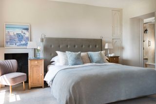 bedroom with a neutral scheme, upholstered headboard and door to ensuite