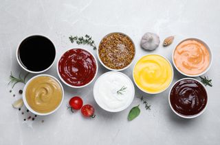 An array of various dipping sauces including ketchup, mustard, BBQ sauce and more, in small bowls.