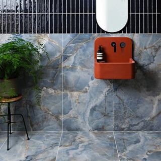 blue marble effect floor and wall tiles in bathroom with red wall mounted sink