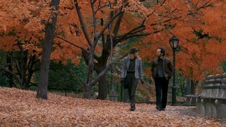 Harry and Sally stroll under autumn leaves in Central Park