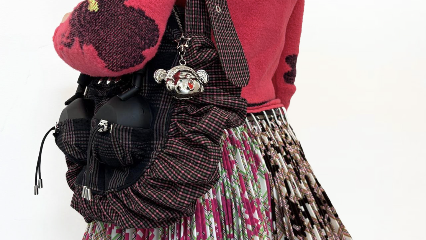 The Sony Chopova Lowena headphones bag, worn by someone wearing a pink cardigan, showing the Sony WH-1000XM6 headphones