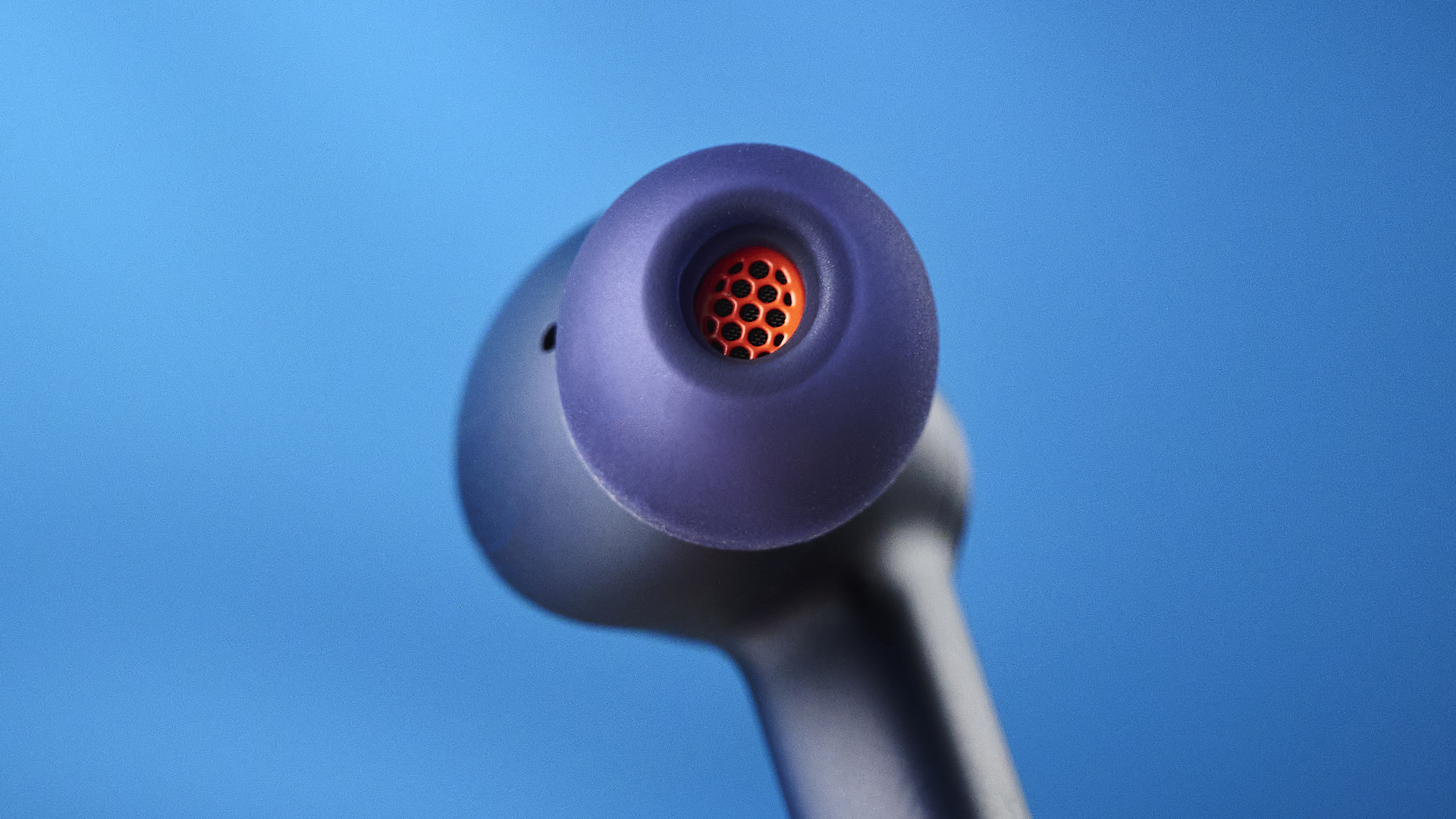 the cambridge audio a100 se earbuds on a blue tom's guide background with a stone-coloured table underneath