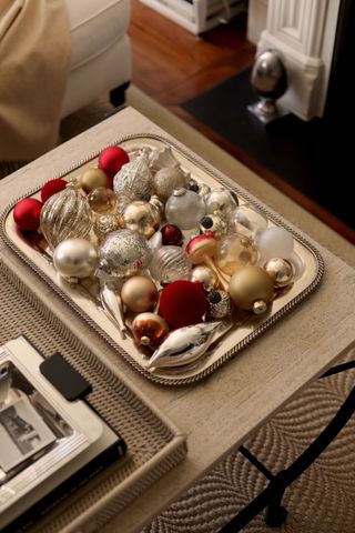 a coffee table with a silver tray filled with christmas ornaments
