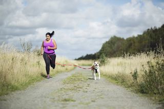 Woman working out how to run faster on a jog with her dog