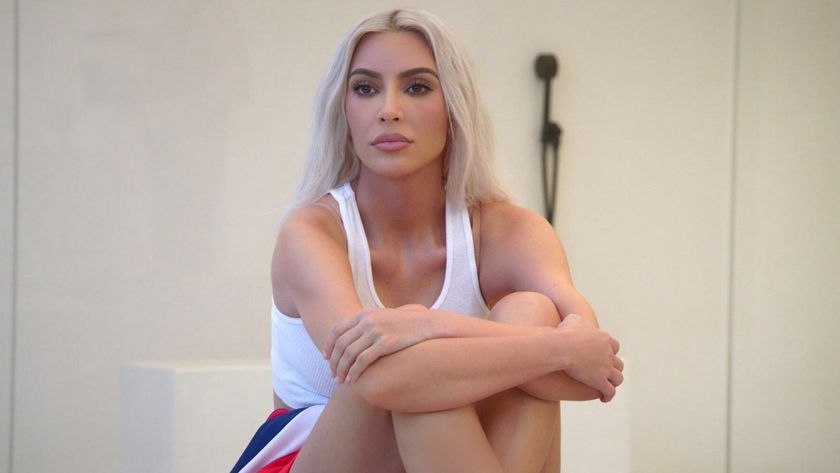 Kim Kardashian sitting with her legs up hugged to her chest in The Kardashians.