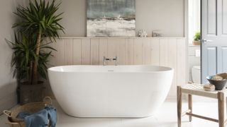 white freestanding bath in front of pale wood panelling on bathroom walls