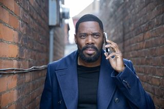 Colman Domingo as Muncie Daniels, holding a cellphone to his ear while standing in a brick alleyway, in Episode 102 of 'The Madness.'