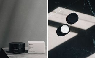 LEFT: A round black pot jar with its grey box packaging next to it, photographed on a grey vinyl top against a grey background; RIGHT: A round black open pot jar showing the contents (white face cream) with the black cover next to it, photographed on a grey surface with shadow