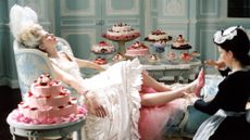 A still from the film adaptation of Marie Antoinette played by Kirsten Dunst, reclining on a chair
