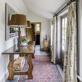 hallway with rug on floor and window with curtains