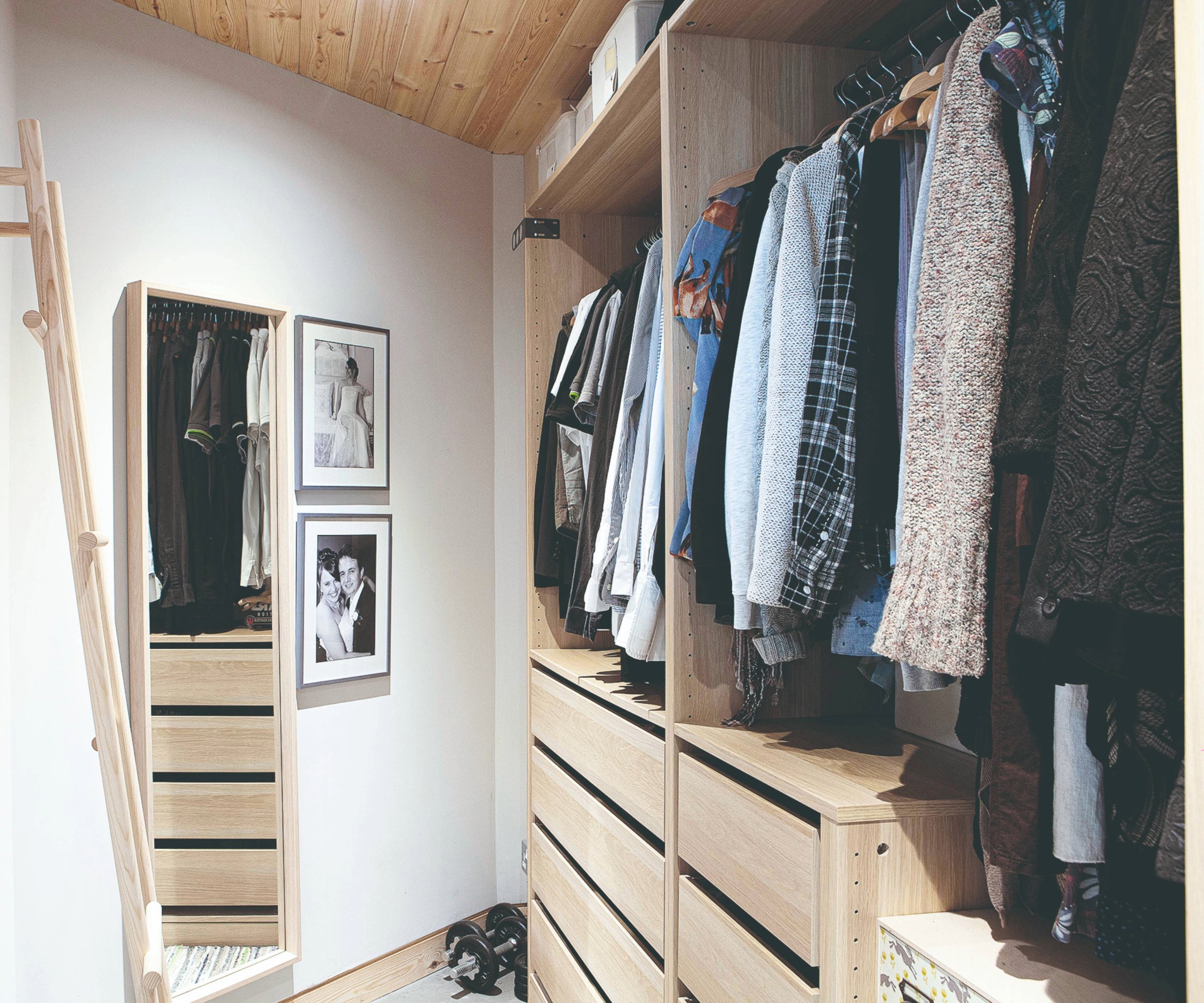 Dressing room with an open wardrobe, mirror, and photographs on the wall