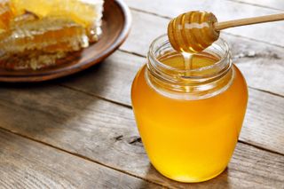 A honey dipper in a jar of honey