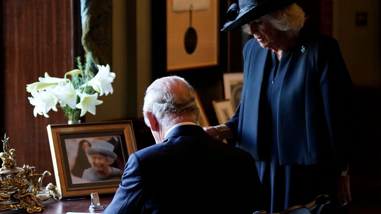 Britain&#039;s Camilla, Queen Consort (R) watches as Britain&#039;s King Charles III signs the visitors&#039; book, alongside an image of his late mother Queen Elizabeth II, at Hillsborough Castle in Belfast on September 13, 2022, during his visit to Northern Ireland. - King Charles III on Tuesday travelled to Belfast where he is set to receive tributes from pro-UK parties and the respectful sympathies of nationalists who nevertheless can see reunification with Ireland drawing closer.