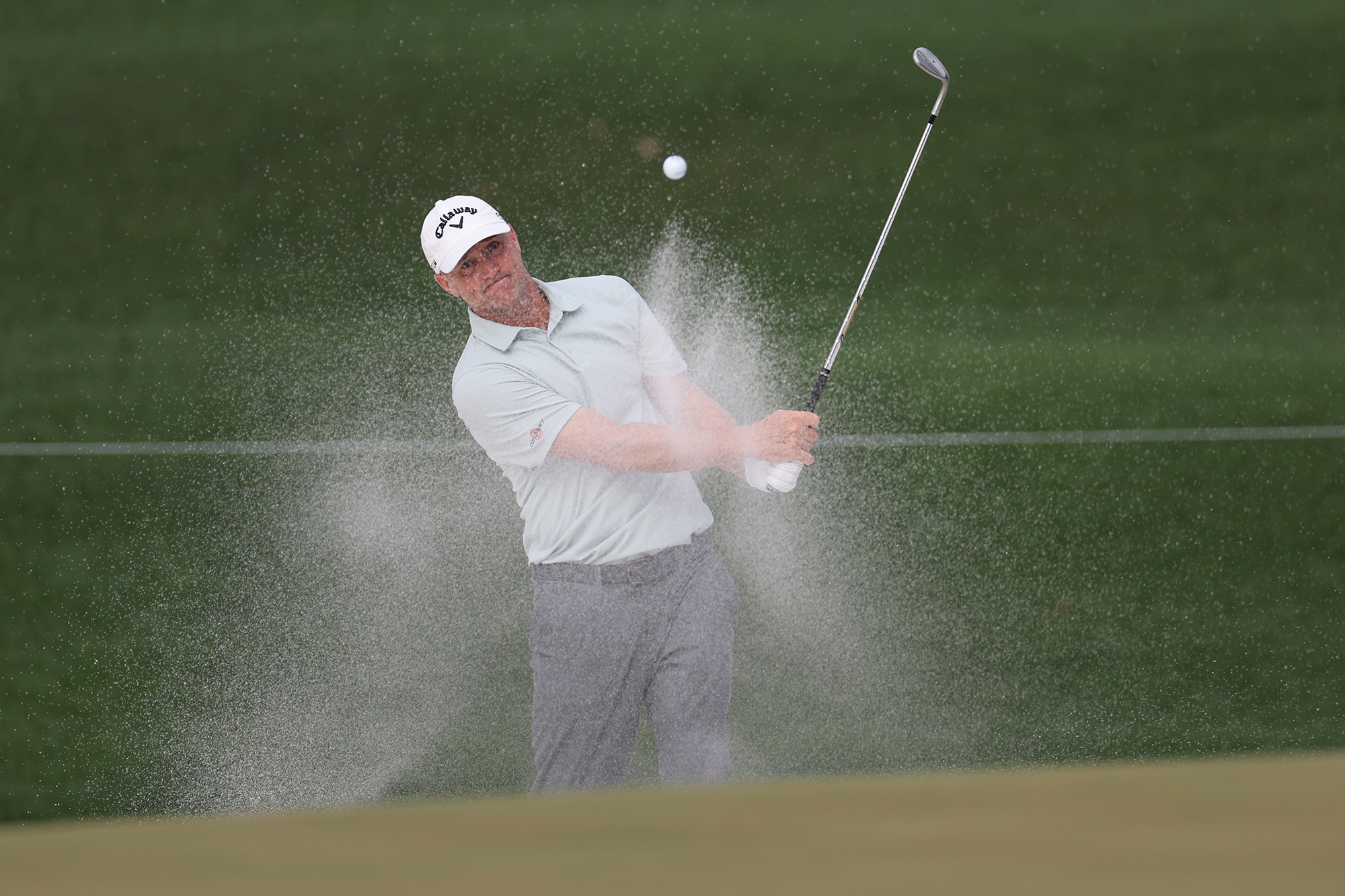 Alex Noren hitting a shot out of a greenside bunker