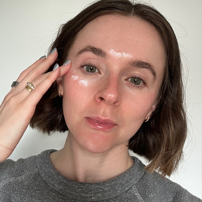 A selfie of Grace Day applying a vitamin c eye cream to her skin