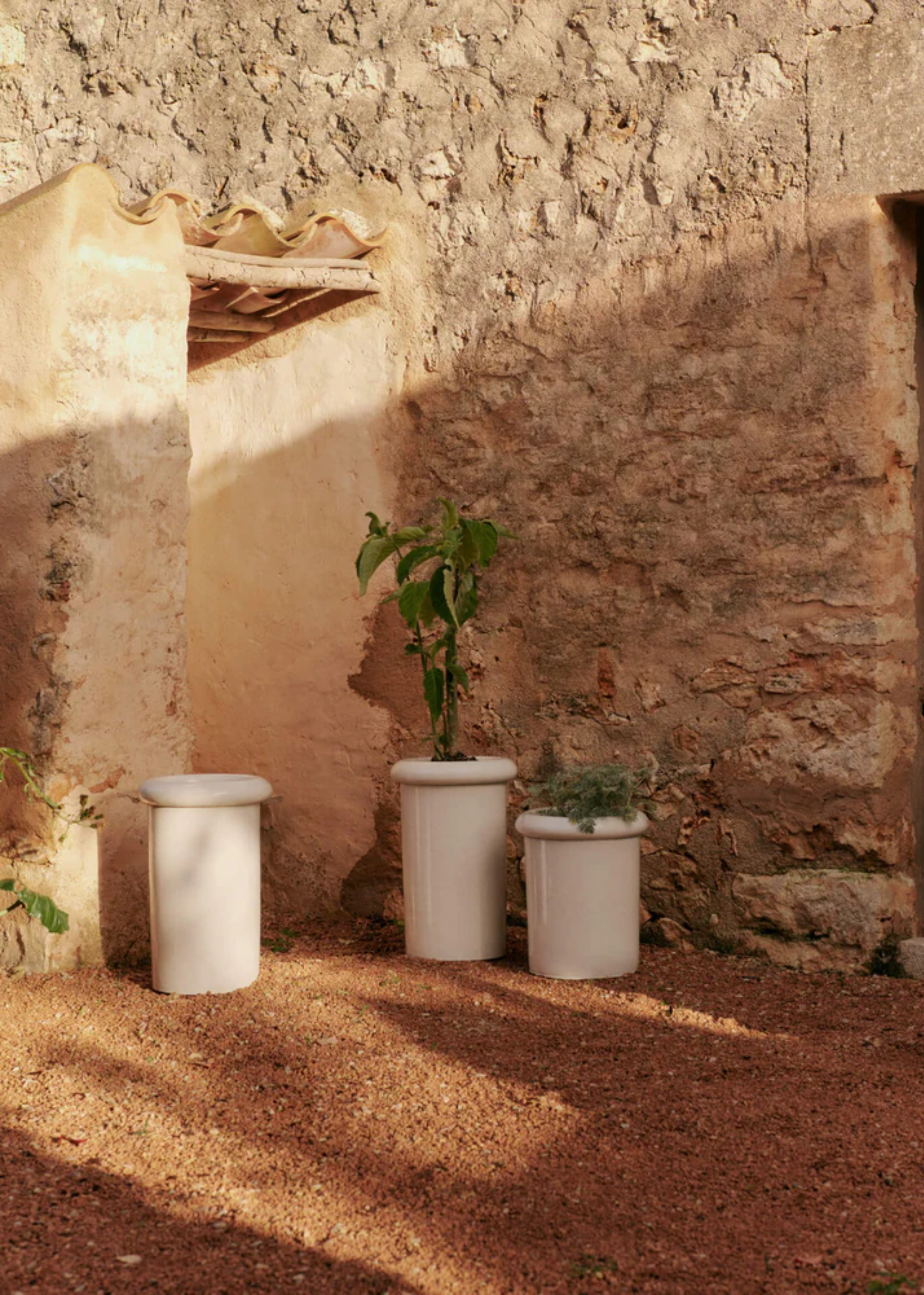 A trio of white planters in an outdoor garden
