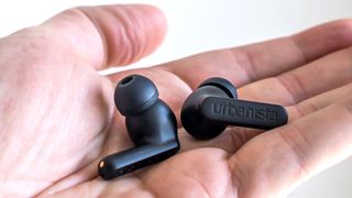 Holding the Urbanista Phoenix earbuds in hand.