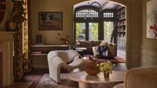 a soft yellow Victorian living room with bold modern decor looking through to a rich green garden room