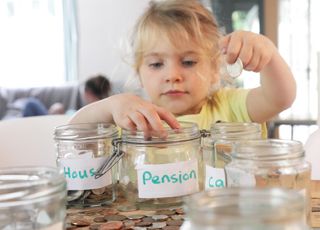 Young girl putting money into savings jars.