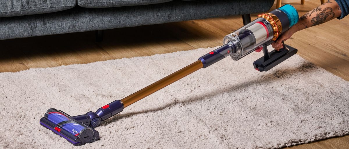 the dyson gen5detect cordless stick vacuum in prussian blue and copper, showing its cleaning head and attachment tools