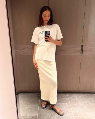 LA woman wears a white The Row maxi skirt, oversize vintage t-shirt and strappy flat sandals.