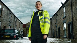 Officer Joanna Marshall (Sophie Rundle) standing in thigh-deep water in a flooded street for After the Flood