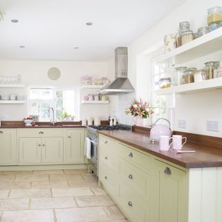 kitchen room with wooden worktop and apple green cabinets with white wall