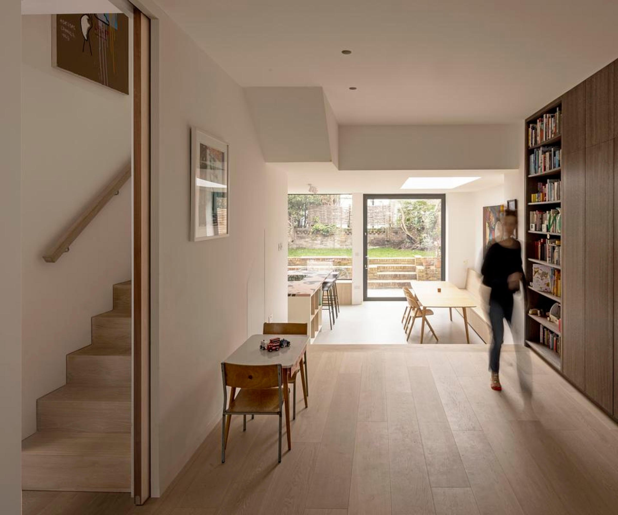 inside of victorian house extension with modern open plan kitchen living dining space and contemporary wooden staircase behind partition wall