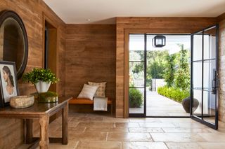 entry hall with wood paneling stone floor and widedoors open to garden