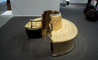 View of the golden version of 'Lathe' by Sebastian Brajkovic - a circular seat with two armrests