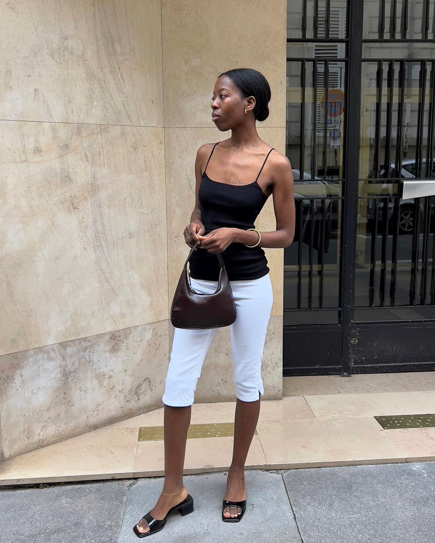 Influencer @sylviemus_ wears a black vest top with with trousers and heeled mules.